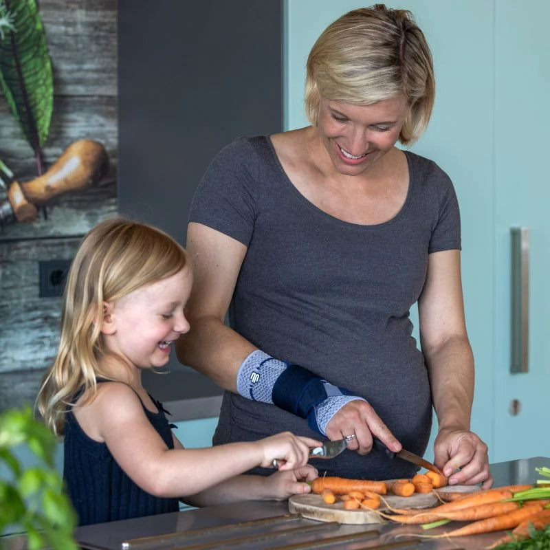 Kvinna som skär morötter i köket med ManuTrain på handleden