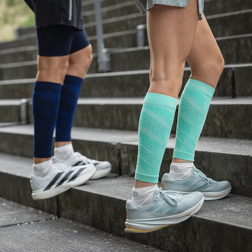 Två personer i Run Performance Compression Sleeves i marinblått och mint går i en trappa