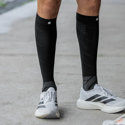 Löpare står i svarta Bauerfeind Run Performance kompressionsstrumpor och vita löparskor