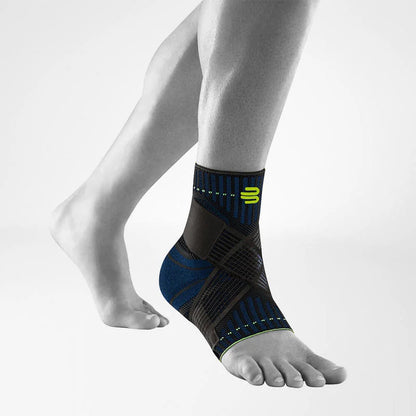 Bauerfeind Sports Ankle Support fotledsstöd i svart med blå detaljer på fot, vit bakgrund
