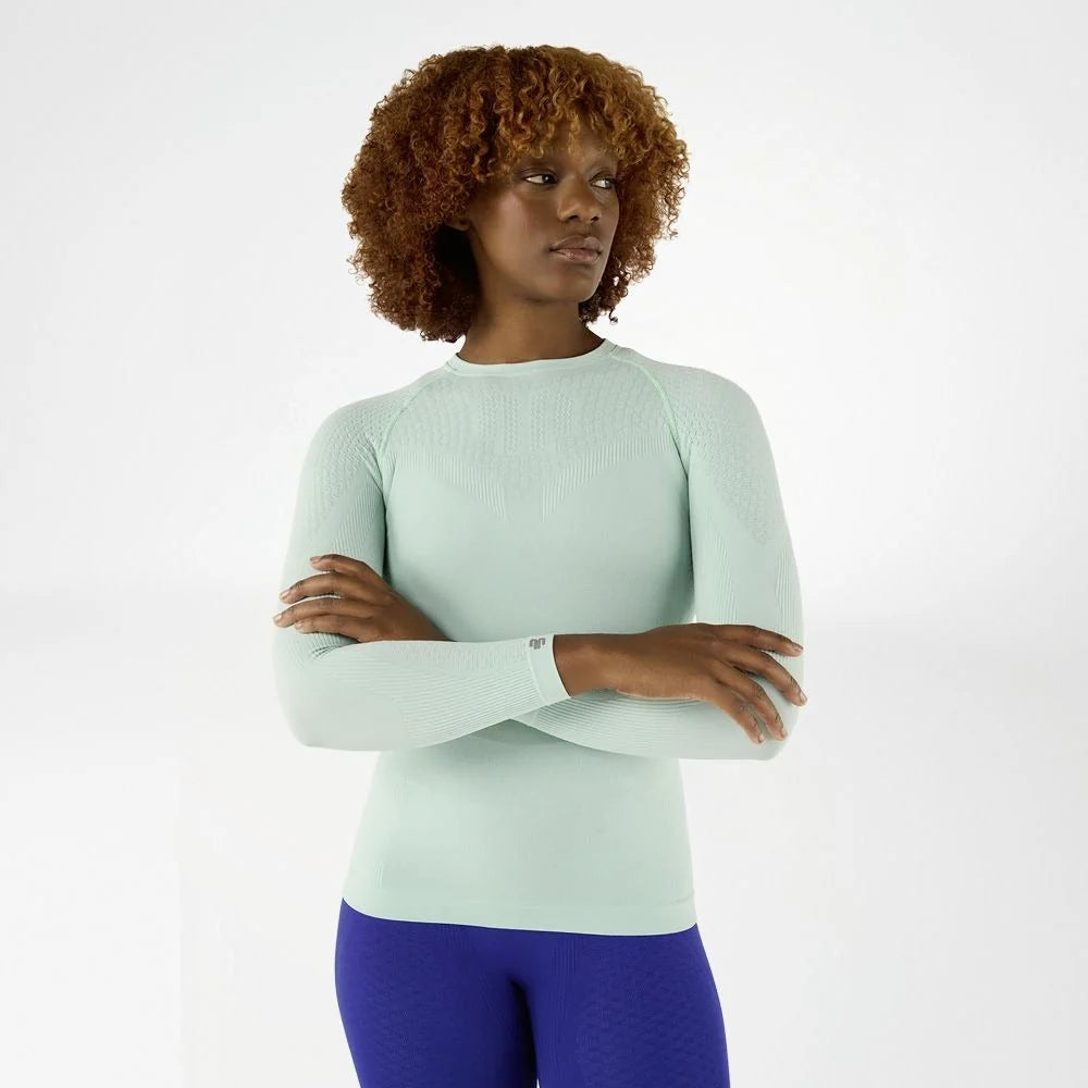 Kvinna i turkos Bauerfeind Sports Compression långärmad tröja, framifrån med armarna i kors