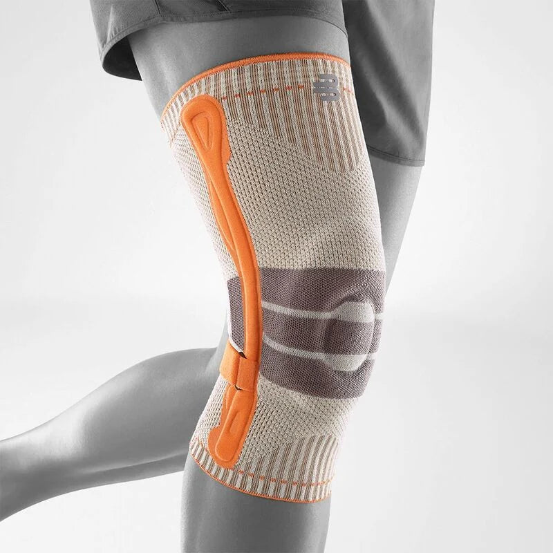 Bauerfeind Sports Outdoor Knee Support i beige med orange remsystem, sett från sidan, vit bakgrund