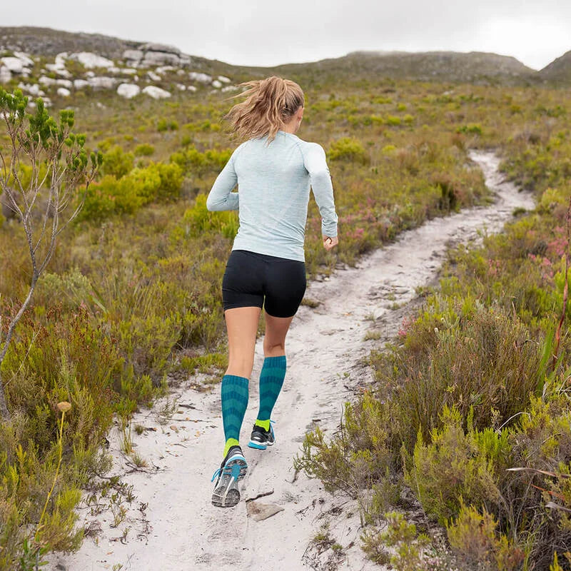 Kvinna springer på grusstig med Bauerfeind Trail Run kompressionsstrumpor