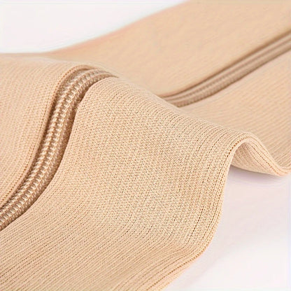 Närbild på det mjuka, elastiska tyget och dragkedjan på beige stödstrumpor.